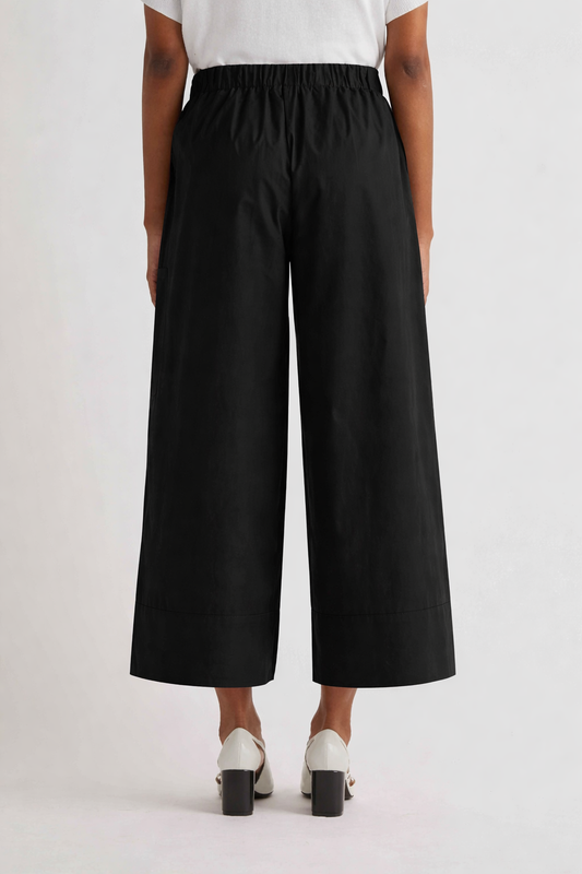 Person wearing black wide-leg pants on a white background